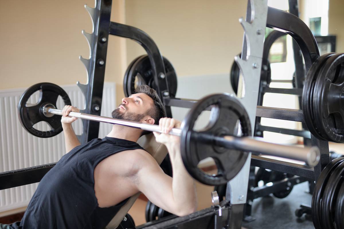 Compact home gym featuring a workout bench with storage holding dumbbells, resistance bands, and towels neatly inside its under-seat compartment